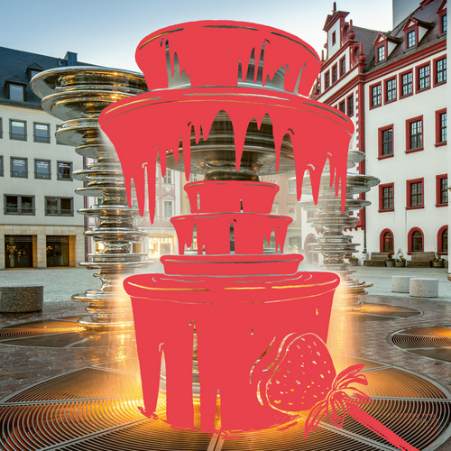 Ein digital bearbeitetes Bild zeigt einen Stadtbrunnen mit einer Grafiküberlagerung, die einem Schokoladenbrunnen mit roter tropfender Schokolade und einer Erdbeere ähnelt. Im Hintergrund sind historische Gebäude auf einem Kopfsteinpflasterplatz zu sehen.